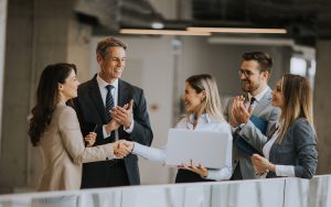 Business professionals shaking hands in an office. Considerations for selecting an outsourcing partner.